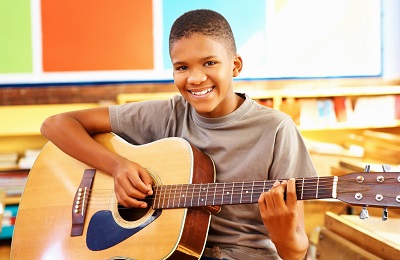 child with a smile holding a  guitar