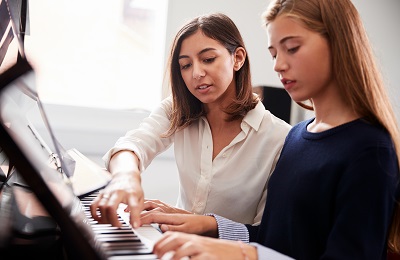 piano teacher and student  sitting at a piano